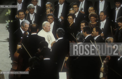 Vatican City, November 1986. Pope John Paul II (Karol Wojtyla) in the Nervi Hall among the musicians of the orchestra of RAI (the Italian public television) after their concert / Città del Vaticano, Novembre 1986. Papa Giovanni Paolo II in Sala Nervi tra i musicisti dellorchestra della RAI dopo il loro concerto - ©Marcello Mencarini/Rosebud2