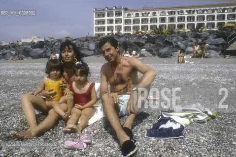 Giardini Naxos (Messina), 1986. Italian comic actor Tullio Solenghi, his wife Laura and their daughters on the beach in front of the Hilton Hotel / Giardini Naxos (Messina), 1986. Lattore comico Tullio Solenghi, sua moglie Laura e le loro due figlie sulla spiaggia davanti all Hotel Hilton - ©Marcello Mencarini/Rosebud2