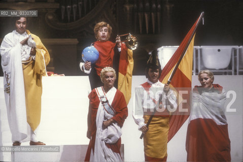 Pesaro, August 18, 1984. Rossini Opera Festival. From the left: bass-baritone Ruggero Raimondi as Don Profondo, basso buffo Enzo Dara as Baron Trombonok, mezzo-soprano Lucia Valentini Terrani as Marchesa Melibea, baritone Leo Nucci as Don Alvaro, soprano Katia Ricciarelli as Madame Cortese in Il viaggio a Reims (The Jorney to Reims) by Gioacchino Rossini. This is the first performance of that opera staged by Luca Ronconi and conducted by Claudio Abbado, after the reconstruction of its manuscript, assumed lost, in the 1970s / Pesaro, 18 agosto 1984. Rossini Opera Festival. Da sinistra: il basso-baritono Ruggero Raimondi nel ruolo di Don Profondo, il basso buffo Enzo Dara nel ruolo del Barone di Trombonok, il mezzosoprano Lucia Valentini Terrani nel ruolo della Contessa Melibea, il baritono Leo Nucci nel ruolo di Don Alvaro, il soprano Katia Ricciarelli nel ruolo di Madame Cortese ne Il viaggio a Reims di Gioacchino Rossini. E la prima rappresentazione dellopera con la regia di Luca Ronconi e la direzione dorchestra di Clauio Abbado, dopo il ritrovamento e la ricomposizione negli anni 70 del suo manoscritto che si credeva perduto - ©Marcello Mencarini/Rosebud2