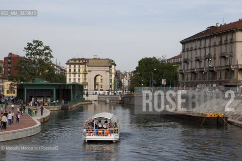 Milan, May 2015. The Milan Darsena after the recent restoration.  This was the old harbour terminal of the Navigli urban canal system,  abandoned and for many years in a state of decay. On the right: an old barge used in the past for carrying goods. On the left: the new indoor market. In the middle: a boat shuttle for tourists / Milano, maggio 2015. La Darsena dopo i recenti lavori di restauro e riqualificazione urbana. Un tempo era il porto della rete dei Navigli, poi abbandonata e rimasta in rovina per molti anni. A destra: una vecchia chiatta destinata un tempo al trasporto fluviale. A sinistra: il nuovo mercato coperto. Al centro: navetta per turisti  - ©Marcello Mencarini/Rosebud2