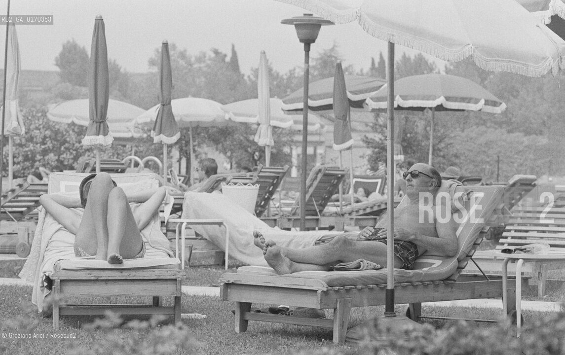 POLITICA / IL MINISTRO DELLA GUERRA INGLESE JOHN PROFUMO (GB) / SDRAIATO SU UN LETTINO IN COSTUME DA BAGNO E CON OCCHIALI NERI / OMBRELLONI /1976 - © ARCHIVIO Graziano Arici/Rosebud2 