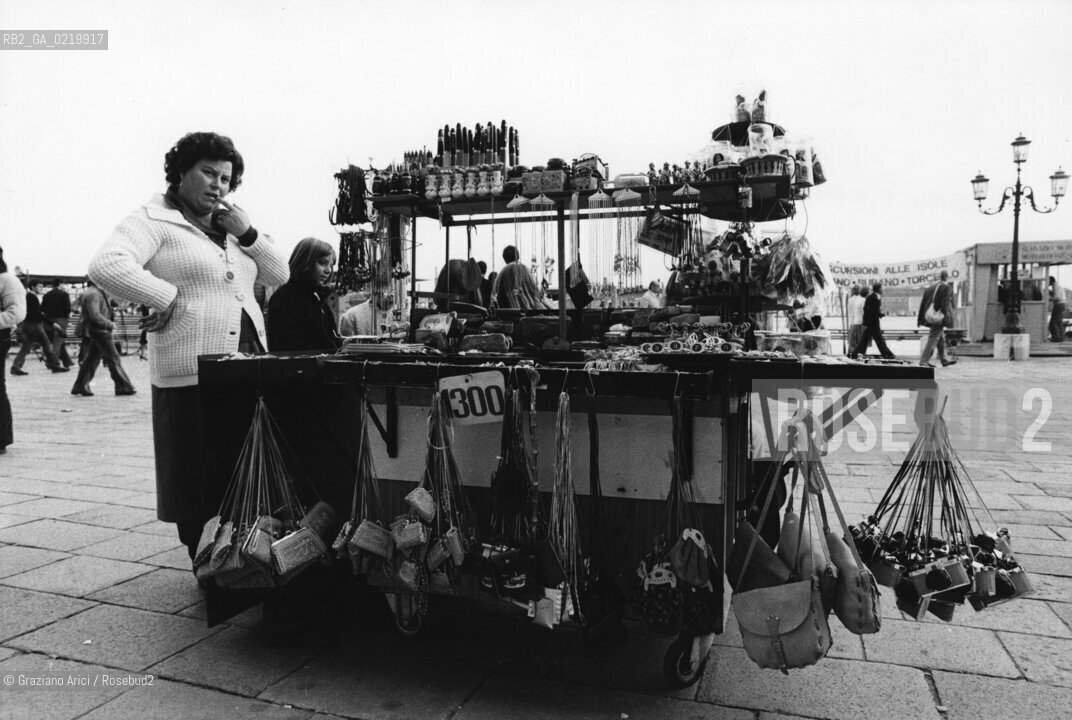 -VENEZIA,1980. VENDITRICE AMBULANTE DI SOUVENIR TURISTICI. TURISMO, VENDITORE, AMBULANTE, PIAZZA SAN MARCO .-VENICE,1980. SOUVENIRS HAWKER IN SAINTS MARK SQUARE  © ARCHIVIO Graziano Arici/Rosebud2 