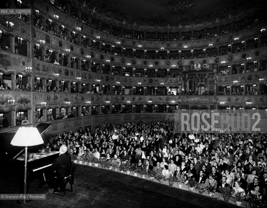 -Venezia, 1963. Teatro La Fenice. Vista del palcoscenico e del pubblico durante un concerto, senza indicazione dellautore. Stampa ai sali dargento, 20x25 cm..-Venice, 1963. Theater La Fenice. Panoramic view of the stage set and the spectators during a concert, silver salt print ,20x25 cm - Archivio Graziano Arici...LArchivio Arici non è riuscito ad avere informazioni sullautore di questa foto. Siamo comunque a disposizione di qualunque avente diritto per riconoscere eventuali proprietà intellettuali che non sia stato possibile fin qui attribuire. .Qualora si fosse inavvertitamente leso qualsiasi diritto di riproduzione, si prega di contattare lArchivio che provvederà a rimuovere le immagini in questione..La cessione dei diritti di questa immagine si intende per quanto di nostra competenza. Non comprende invece le eventuali spese  relative a diritti che potranno essere richiesti dagli Enti o persone fisiche cui appartengono eventualmente i soggetti  ripresi. Tali costi, ove necessari, e l’espletamento di qualsivoglia pratica di richiesta di concessione del permesso di pubblicazione sono esclusivamente a carico e a cura del soggetto acquirente di questa immagine.  astga ©Graziano Arici/Rosebud2