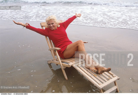 Caption: Nome: .MILO SANDRA.Descrizione: .CINEMA ATTRICE / AL MARE / SU SEDIA A SDRAIO / INDOSSA UN ABITO ROSSO.Credit: ©Graziano Arici/Rosebud2 / Costo: .A.Nazione: .ITALIA.Cittˆ: ..Data: .1988