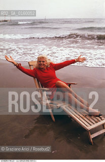 Nome: .MILO SANDRA.Descrizione: .CINEMA ATTRICE / AL MARE / SU SEDIA A SDRAIO / INDOSSA UN ABITO ROSSO.Credit: ©Graziano Arici/Rosebud2 / Costo: .A.Nazione: .ITALIA.Cittˆ: .VENEZIA.Data: .1988.