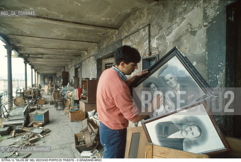 Nome: .REGIONE ISTRIA.Descrizione: .IL SILOS 26 CHE CONTIENE OGGETTI E MASSERIZIE DEI PROFUGHI ESULI ISTRIANI DEL DOPOGUERRA / SOTTO LA TUTELA DELLI.R.C.I. NEL VECCHIO PORTO / RAGAZZO CHE PULISCE LE FOTO SEDIE.Credit: ©Graziano Arici/Rosebud2 / Costo: .A.Nazione: ..Cittˆ: .TRIESTE.Data: .1995