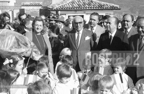 INDUSTRIA ECONOMIA / LARMATORE ACHILLE LAURO (ITALIA) CON GLI OCCHIALI NERI INSIEME ALLA MOGLIE A LONGARONE  / MAZZO DI FIORI, BAMBINI IN GREMBIULE CON BANDIERINE /1971 - © ARCHIVIO Graziano Arici/Rosebud2 