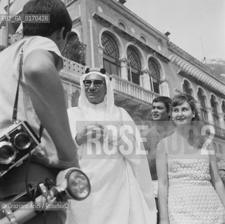 LO SCEICCO DEL KUWAIT ABDULLAH AL SABAH CON LA MOGLIE ALAH DAVANTI ALLHOTEL EXCELSIOR / FOTOGRAFO, MACCHINA FOTOGRAFICA / MOSTRA INTERNAZIONALE DARTE CINEMATOGRAFICA, BIENNALE 1966 - © ARCHIVIO Graziano Arici/Rosebud2 
