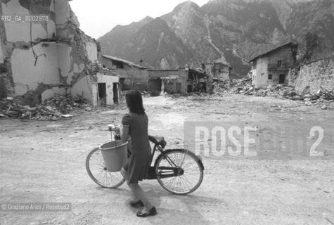 TARCENTO1976 DONNA CHE PASSA CON LA BICICLETTA DAVANTI ALLE MACERIE  DOPO IL TERREMOTO NEL FRIULI ©ARCHIVIO Graziano Arici/Rosebud2 TERREMOTO FRIULI VENEZIA GIULIA CATASTROFI AMBIENTALI CASE DISTRUTTE ROVINE MACERIE