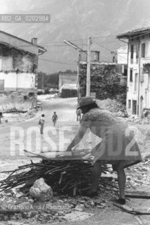 TARCENTO 1976 DONNA CHE RACCOGLIE LA LEGNA DOPO IL TERREMOTO NEL FRIULI © ARCHIVIO Graziano Arici/Rosebud2  TERREMOTO FRIULI VENEZIA GIULIA CATASTROFI AMBIENTALI CASE DISTRUTTE ROVINE MACERIE DONNA LEGNA