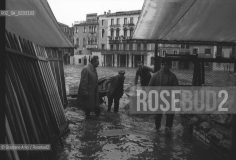 VENEZIA 1976 UOMO CHE LAVORANO NELLACQUA ALTA © ARCHIVIO Graziano Arici/Rosebud2  ACQUA ALTA CALLE MERCATO CARRETTO PROBLEMI VENEZIA