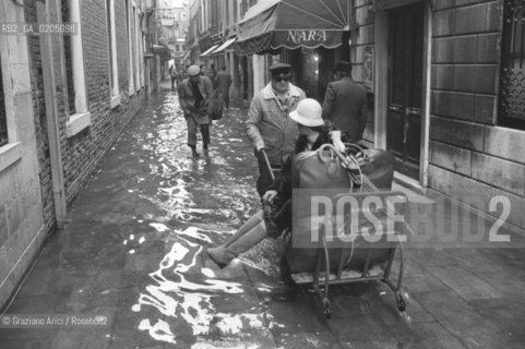 VENEZIA 1981 ACQUA ALTA IN CALLE © ARCHIVIO Graziano Arici/Rosebud2  ALTA MAREA PROBLEMI DISAGI VENEZIA UOMO CON CARRETTO PORTAPERSONE