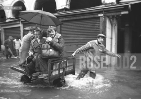 VENEZIA 1981 ACQUA ALTA IN CALLE © ARCHIVIO Graziano Arici/Rosebud2  ALTA MAREA PROBLEMI DISAGI VENEZIA UOMO CON CARRETTO PORTAPERSONE FACCHINO RIALTO