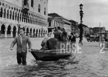 Venice,1959.  Alta marea davanti a Palazzo Ducale: alcuni uomini spingono una barca con persone a bordo. High tide in St Marks Square, in front of the Palazzo Ducale. acqua; alta marea; Ducale - La cessione dei diritti si intende per quanto di nostra competenza; non comprende invece le eventuali spese relative a diritti che potranno essere richiesti dagli Enti cui appartengono le opere riprese. Tali costi, ove neccessari, e l’espletamento di qualsivoglia pratica di richiesta permessi sono esclusivamente  a  carico del committente.  © ARCHIVIO Graziano Arici/Rosebud2 