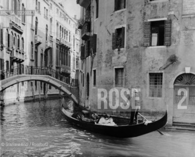 Venice,1955. Gondola con passeggeri o turisti lungo un canale interno alla città. Gondola with passengers winds through the watery streets of Venice. Gondola;turismo © ARCHIVIO Graziano Arici/Rosebud2 