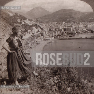 Salerno, fine  1800?. Veduta panoramica del porto di Salerno con ragazza, nei pressi di San Cipriano. On the sunny shores of southern Italy, Salerno and the bay sheltered by  distant Mount Cipriano - La cessione dei diritti si intende per quanto di nostra competenza; non comprende invece le eventuali spese relative a diritti che potranno essere richiesti dagli Enti cui appartengono le opere riprese. Tali costi, ove neccessari, e l’espletamento di qualsivoglia pratica di richiesta permessi sono esclusivamente  a  carico del committente. © ARCHIVIO Graziano Arici/Rosebud2 