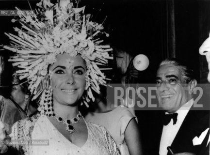 - Venezia, 1967. Ritratto dellattrice Liz Taylor durante un party di Carnevale insieme al magnate greco Aristote Onassis.-Venice, 1967.Portrait of the actress Liz Taylor and the greek magnate Aristote Onassis during an carnival party organised by Joe Picone. Carnevale Attrice Magnate ritratto - La cessione dei diritti si intende per quanto di nostra competenza; non comprende invece le eventuali spese relative a diritti che potranno essere richiesti dagli Enti cui appartengono le opere riprese. Tali costi, ove neccessari, e l’espletamento di qualsivoglia pratica di richiesta permessi sono esclusivamente  a  carico del committente. © ARCHIVIO Graziano Arici/Rosebud2 