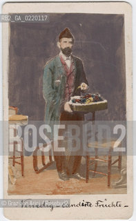 -VENEZIA, COLOMBO COEN E FIGLIO FOTOGRAFO, ANTE 1866?,RITRATTO IN STUDIO POSATO DI VENDITORE DI FRUTTI CANDITI,STAMPA ALLALBUMINA INCOLLATA SU CARTONE COLORATA A MANO, CARTE DE VISITE, CM 6,5X10,5.FOTOANTICHE POSATO RITRATTO  .-VENICE, COLOMBO COEN E FIGLIO PHOTOFRAPHER, ANTE 1866?, PORTRAIT OF FRUITS VENDER ALBUMEN PHOTOGRAPH MOUNTED ON CARDBOARD HAND COLOURED, CARTE DE VISITE CM 6,5X10,5 © ARCHIVIO Graziano Arici/Rosebud2 .