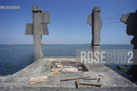 Caption: Nome:..ISOLA DI SANTANGELO DELLA POLVERE....Localizzazione:..VENEZIA / ISOLA DI SANTANGELO DELLA POLVERE / LAGUNA SUD..VENICE / THE ISLE OF SANTANGELO DELLA POLVERE  / THE SOUTH LAGOON..Soggetto:..ISOLA DI SANTANGELO DELLA POLVERE / RESTI  ..THE ISLE OF SANTANGELO DELLA POLVERE / REMAINS  ..Cronologia:......Autore:......Stile:......Editori Stampatori:.... ..Committenza:......Materia e Tecnica:......Collocazione:......Note:..DI ORIGINARIA DESTINAZIONE CONVENTUALE (1060) DALLA SECONDA METÀ DEL XVI SECOLO VENNE UTILIZZATA FINO AL 1946 PER IMPIANTI MILITARI ..ORIGINALLY ESTABLISHED  AS THE SITE OF A MONASTERY (1060) THE ISLAND WAS USED FOR MILITARY PURPOSES FROM THE MID-SIXTEENTH CENTURY UNTIL 1946..Riproduzione Fotografica:..Graziano Arici/Rosebud2 ...Copyright:..Graziano Arici / rosebud2/....Data:..1993....Costo:..A....Key:..ISOLE ABBANDONATE..UNINHABITED ISLANDS