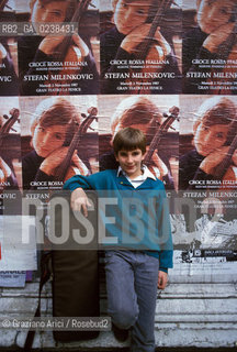 Venezia,1987.Il violinista Stefan Milenkovic mentre visita la città sullo sfondo i poster che lo ritraggono.Musica classica violinista violino ritratto.Venice,1987.The violinist Yugoslav Stefan Milenkovic while making a city tour ©Graziano Arici/Rosebud2