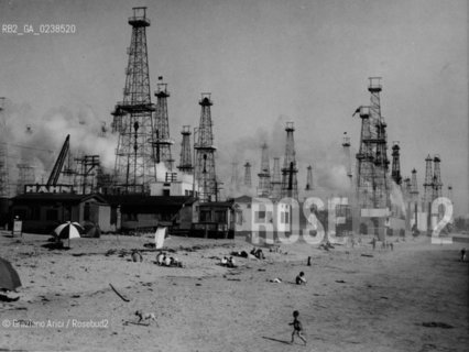 -Venice Beach California (USA), 1930, Spiaggia di Venice Beach, Pozzi petroliferi a ridosso della spiaggia e di case abitate a rischio di incendio,senza indicazione dellautore, stampa ai sali dargento, 15x20 cm..-Venice Beach,California, 1930. Extreme fire hazard : the Los Angeles fire commissioners have branded this booming three month old oilfield among the modest homes and cottages of Venice Beach (California),no authors indication, silver salt print ,15x20 cm - Archivio Graziano Arici..LArchivio Arici non è riuscito ad avere informazioni sullautore di questa foto. Siamo comunque a disposizione di qualunque avente diritto per riconoscere eventuali proprietà intellettuali che non sia stato possibile fin qui attribuire. .Qualora si fosse inavvertitamente leso qualsiasi diritto di riproduzione, si prega di contattare lArchivio che provvederà a rimuovere le immagini in questione..La cessione dei diritti di questa immagine si intende per quanto di nostra competenza. Non comprende invece le eventuali spese  relative a diritti che potranno essere richiesti dagli Enti o persone fisiche cui appartengono eventualmente i soggetti  ripresi. Tali costi, ove necessari, e l’espletamento di qualsivoglia pratica di richiesta di concessione del permesso di pubblicazione sono esclusivamente a carico e a cura del soggetto acquirente di questa immagine...  astga ©Graziano Arici/Rosebud2