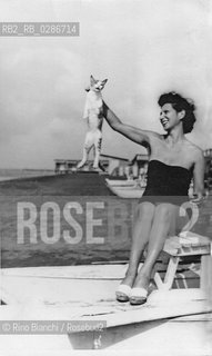 Ostia July 1955..A young woman by the sea, photographed while playing with a cat/.Una giovane donna al mare fotografata mentre gioca con un gatto.Photo: Anonimous/RINO BIANCHI COLLECTION ©Rino Bianchi/Rosebud2