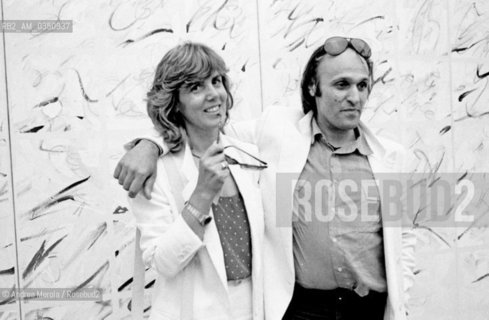 Mario Schifano, pittore, fotografato con la moglie Monica accanto una sua opera, alla Biennale Arte di Venezia, giugno 1982..Italian painter Mario Schifano and his wife Monica pose next his work, at Biennale Modern Art Exhibition, june 1982 Venice.. ©Andrea Merola/Rosebud2