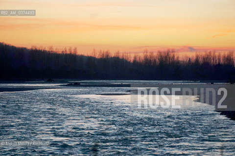 Una panoramica sul fiume Piave al tramonto, in località Isola dei Morti; sullo sfondo la sagoma delle colline del Montello..LIsola dei Morti è una insenatura del fiume Piave, dal fondale basso e ghiaioso, dove frequentemente si arenavano i cadaveri dei soldati, trascinati dalla corrente..Il paese di Moriago, ribatezzato Moriago della Battaglia, nel 1918 si trovò nel mezzo del cosidetto fronte del Piave, tra lesercito italiano posizionato sulle colline del Montello, e lesercito austriaco a valle, il fiume e il centro abitato come terra di nessuno. Gli abitanti sfollarono per la maggior parte, anche se alcuni rimasero a custodia delle case, che però vennero in gran parte distrutte dai bombardamenti di entrambi gli schieramenti..Finita la Grande Guerra, la popolazione di Moriago fu insignita dellonoreficenza della Medaglia dOro al Valore Civile. © Andrea MEROLA  .An overview of the Piave river at sunset, in Isola dei Morti; in the background the silhouette of the Montello hills..The Island of the Dead is an inlet of the Piave river, with a shallow, gravelly bottom, where the corpses of soldiers, frequently dragged by the current, ran aground..The town of Moriago, renamed Moriago della Battaglia, in 1918 found itself in the middle of the so-called front of the Piave, between the Italian army positioned on the hills of Montello, and the Austrian army downstream, the river and the inhabited center as a land of nobody. The inhabitants displaced for the most part, although some remained in custody of the houses, which however were largely destroyed by the bombing of both sides..After the Great War, the population of Moriago was awarded the honor of the Gold Medal to Civil Value.  ©Andrea Merola/Rosebud2