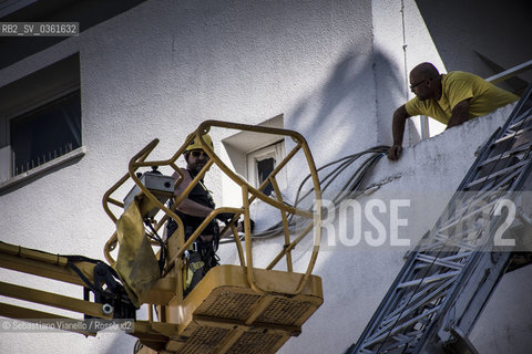 Lido di Venezia, 21 Agosto 2017. Lavori di allestimento del Palazzo del Cinema per la 74a edizione della Mostra Internazionale del Cinema di Venezia. Due operai fissano dei cavi elettrici allesterno del palazzo del Cinema.  ©Sebastiano Vianello/Rosebud2