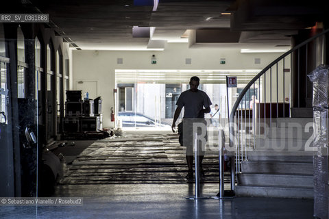 Lido di Venezia, 21 Agosto 2017. Lavori di allestimento del Palazzo del Cinema per la 74a edizione della Mostra Internazionale del Cinema di Venezia. Landrone del Palazzo del Cinema in allestimento, con materiali imballati, materiali eletrici e e un operaio che cammina in controluce. ©Sebastiano Vianello/Rosebud2