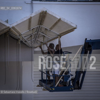 Lido di Venezia, 21 Agosto 2017. Lavori di allestimento del Palazzo del Cinema per la 74a edizione della Mostra Internazionale del Cinema di Venezia. Lesterno del Palazzo del Cinema condue operai che lavorano  allallestimento dellilluminazione della pensilina. ©Sebastiano Vianello/Rosebud2