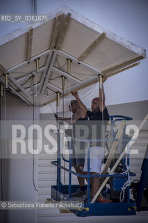 Lido di Venezia, 21 Agosto 2017. Lavori di allestimento del Palazzo del Cinema per la 74a edizione della Mostra Internazionale del Cinema di Venezia. Lesterno del Palazzo del Cinema condue operai che lavorano  allallestimento dellilluminazione della pensilina. ©Sebastiano Vianello/Rosebud2